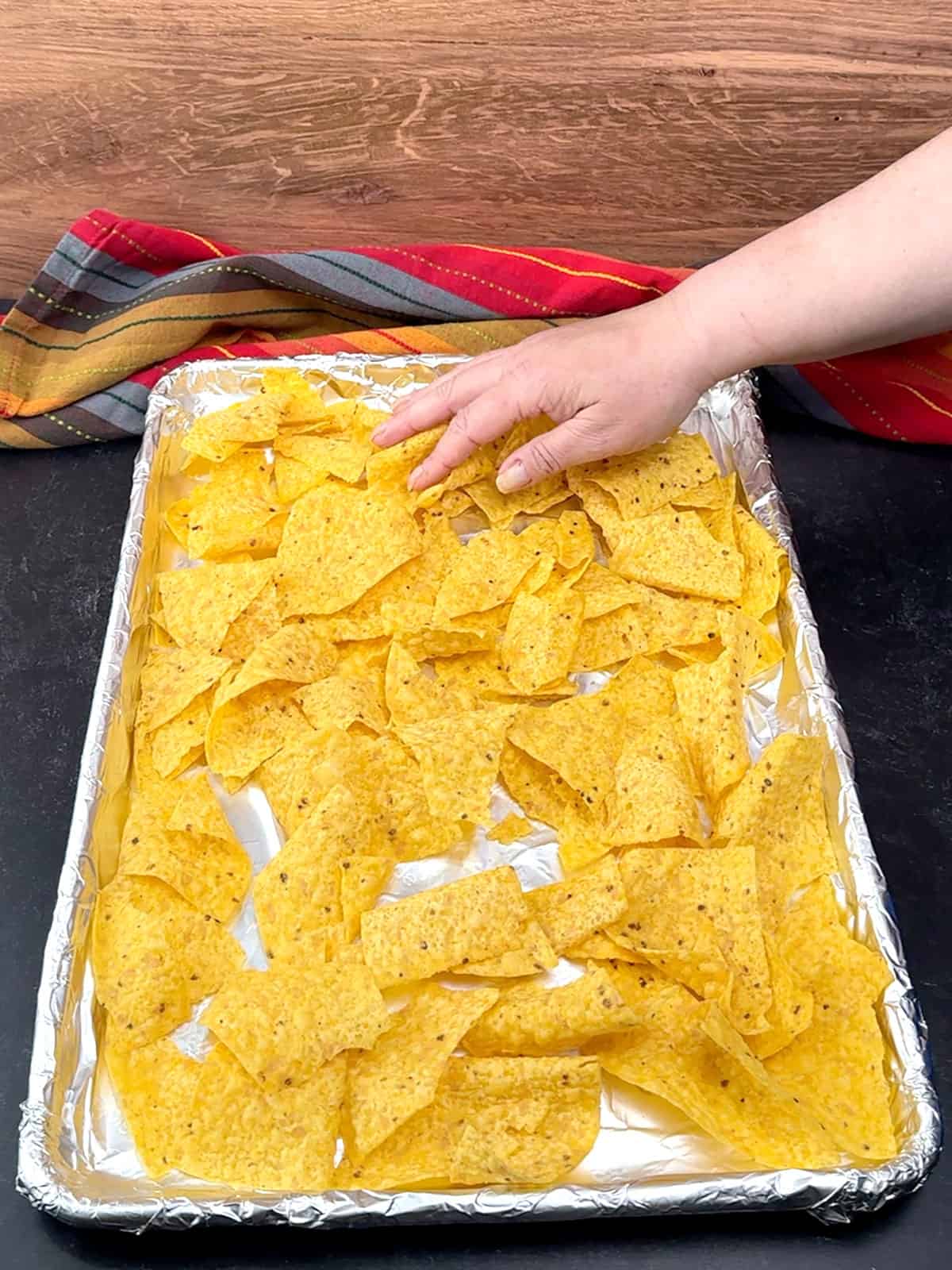 spreading first half of tortilla chips on prepared pan