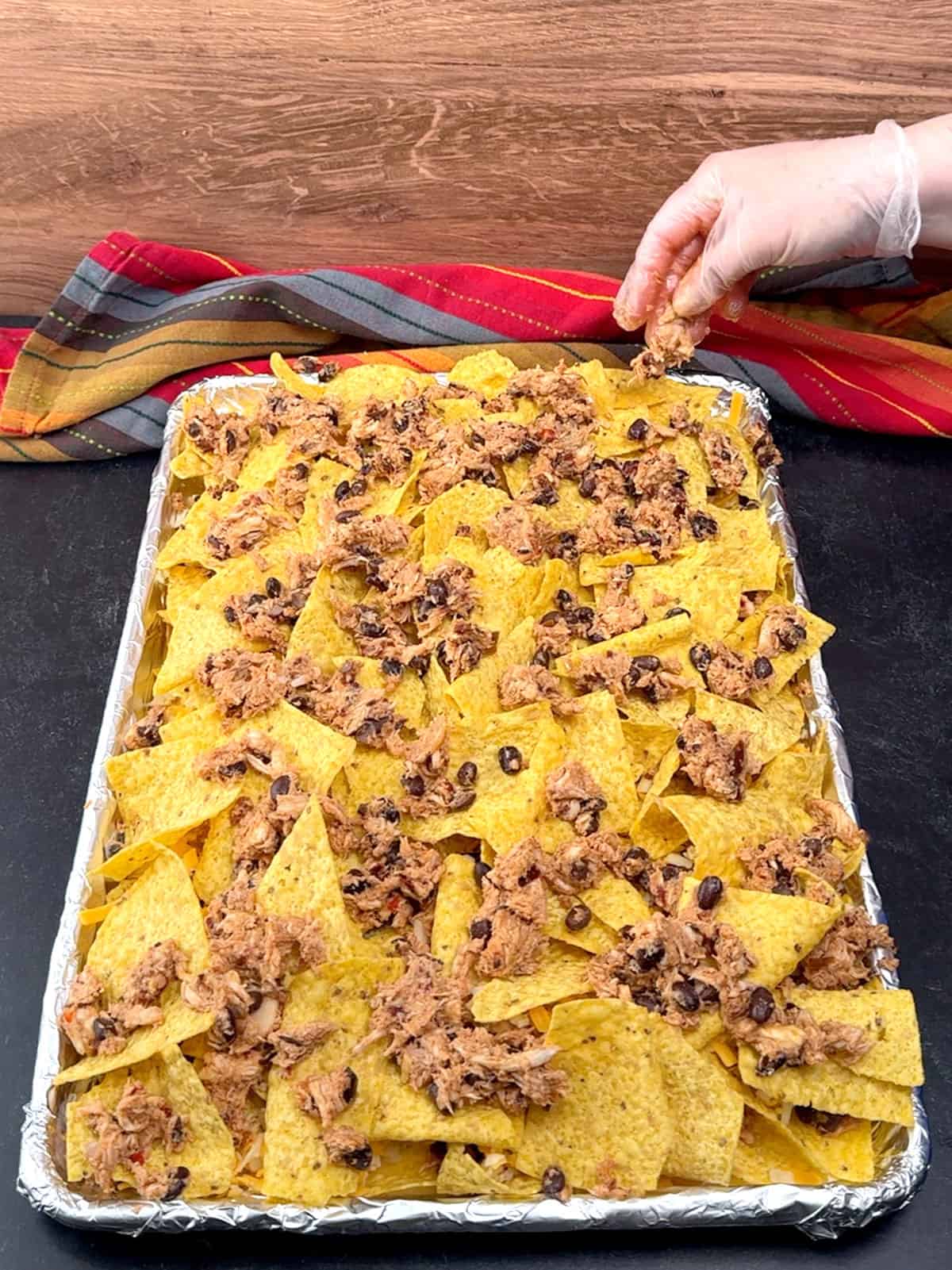 sprinkling remaining chicken over second layer of tortilla chips