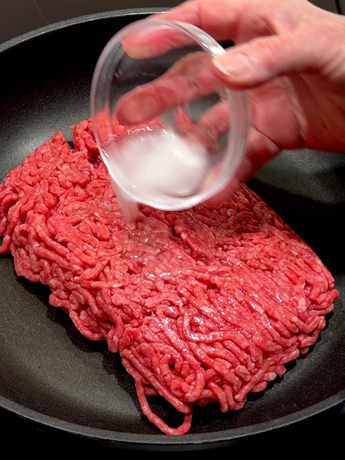Adding baking soda mixed with water to ground beef before cooking to enhance its tenderness.