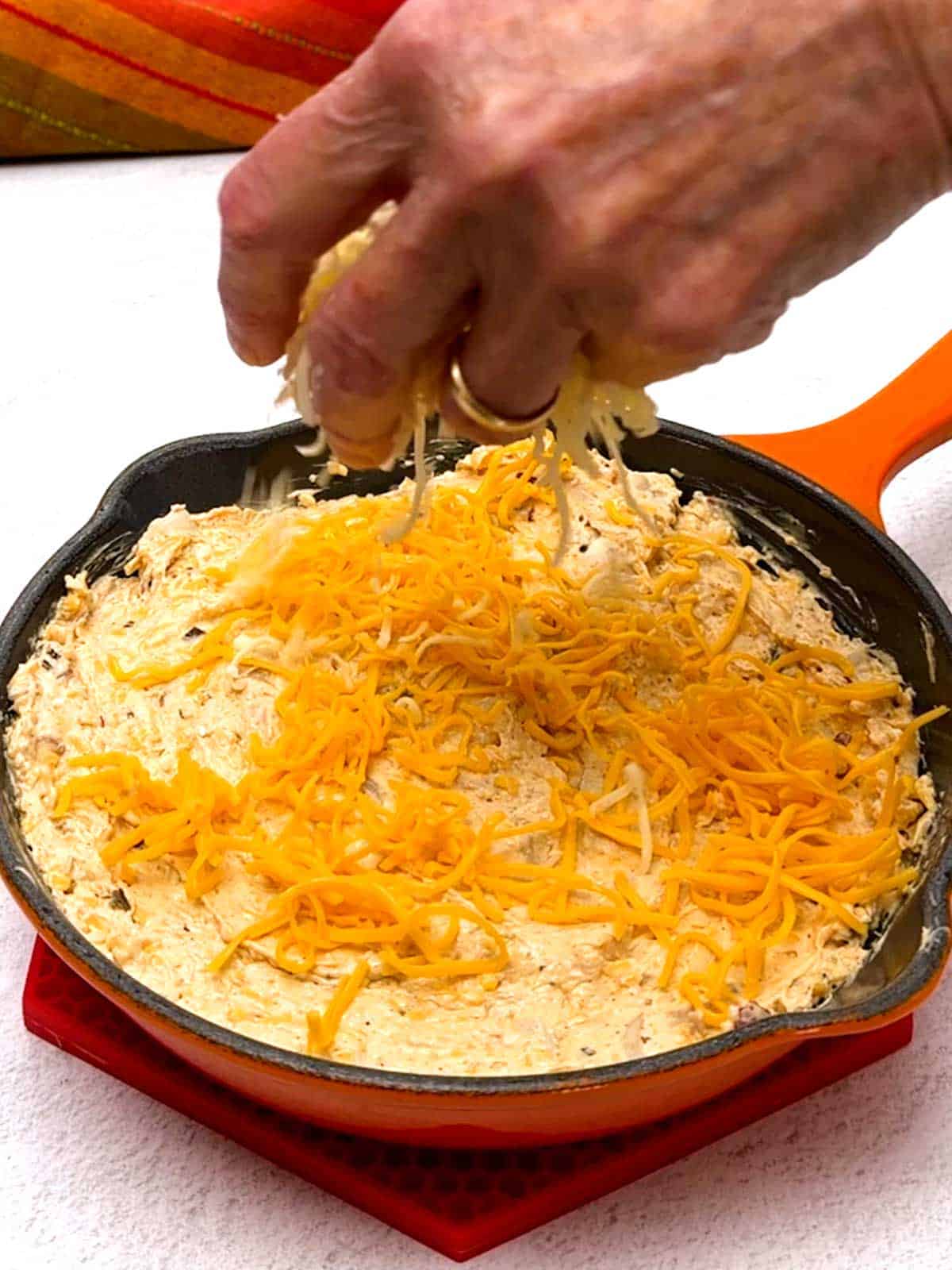 Sprinkling reserved Monterey Jack cheese on the dip.