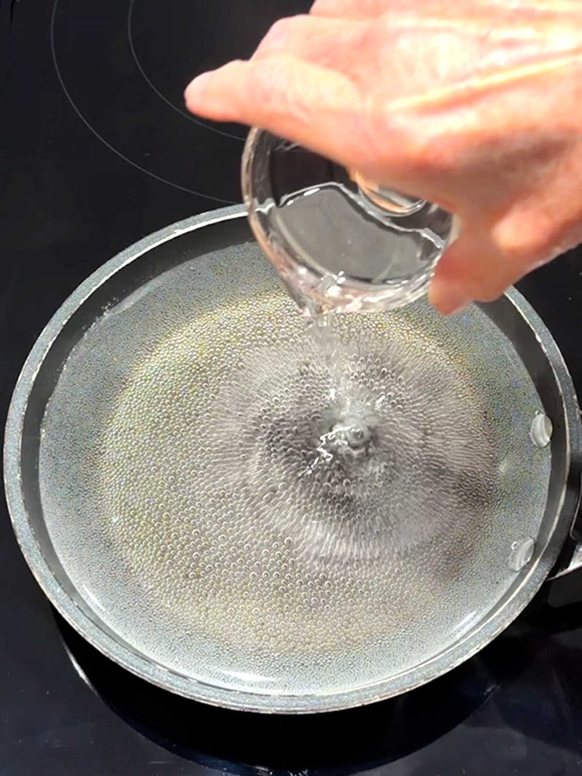 Adding white vinegar to the simmering water.