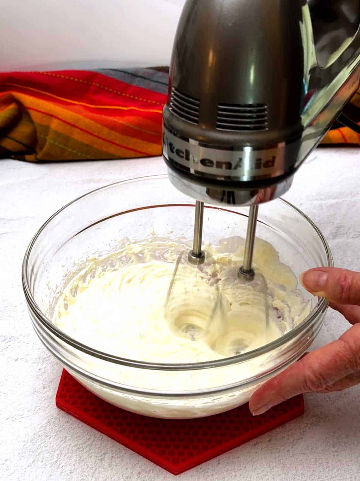 Beating the cream cheese and sour cream in a glass bowl.