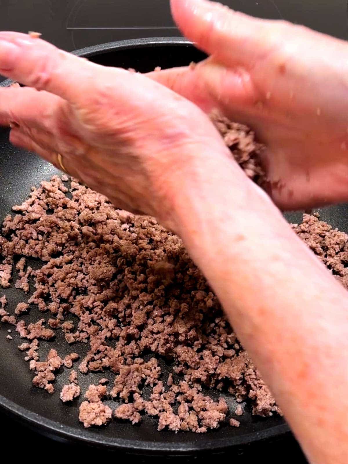 Crumbling cooked ground beef between my palms.