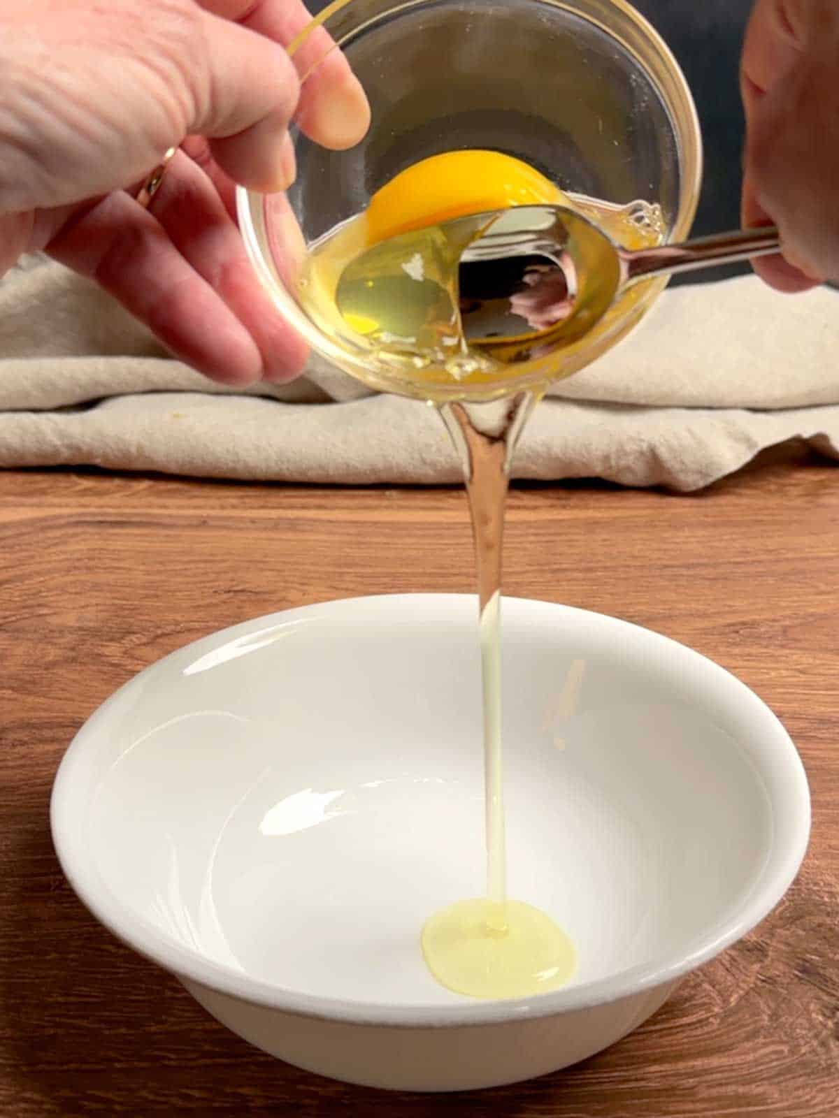 Draining the loose white from the egg using the spoon method.