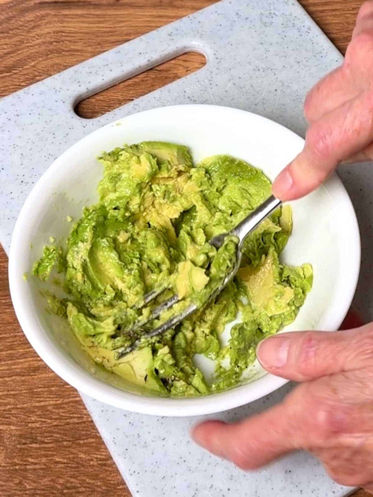 Mashing avocado with a fork.