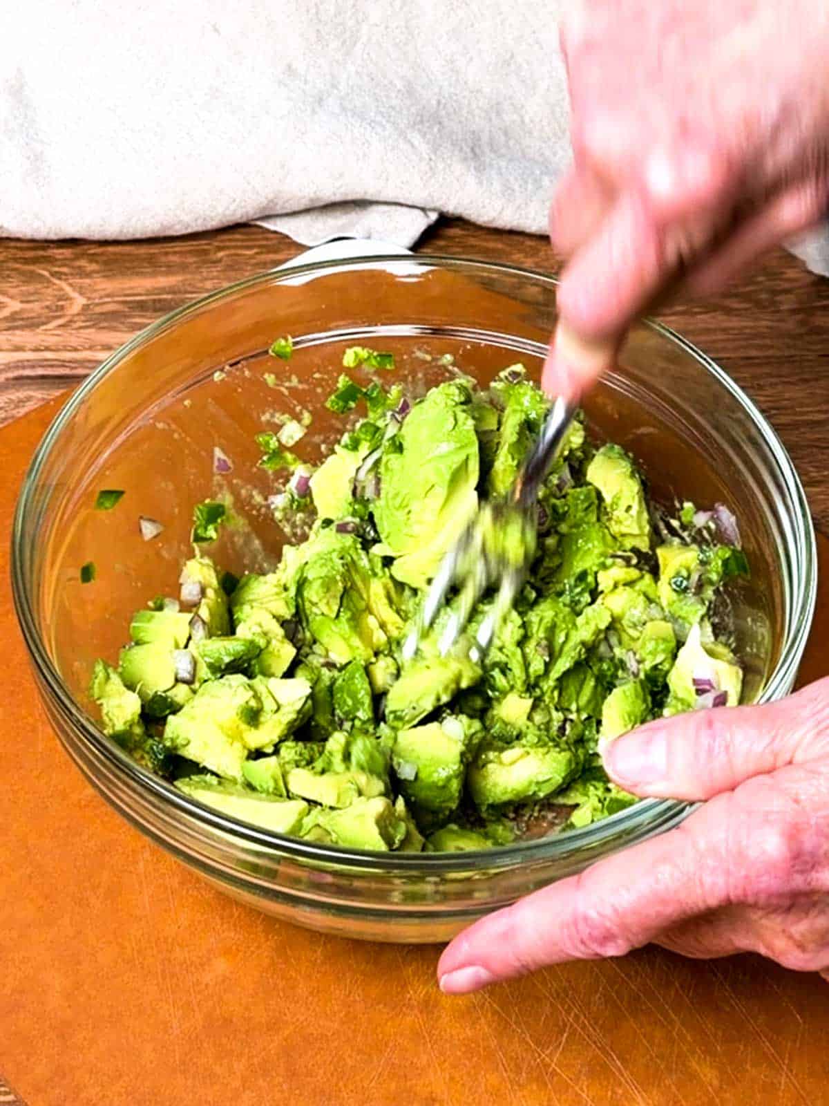 Mashing the avocado mixture with a fork.