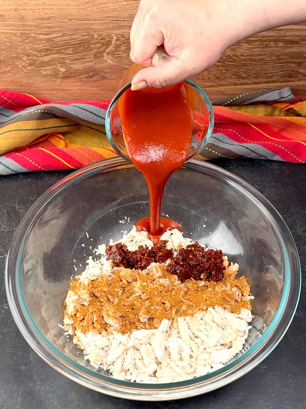 adding taco seasoning chipotle peppers, and taco sauce to shredded rotisserie chicken