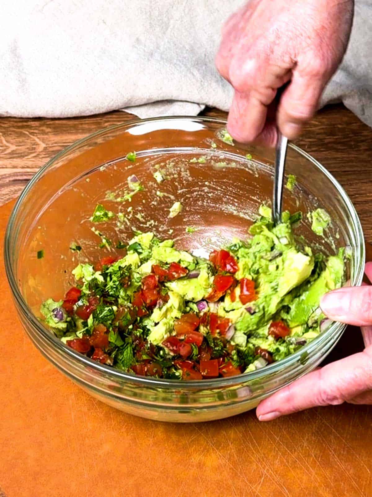 Mixing the fresh ingredients into the guacamole.