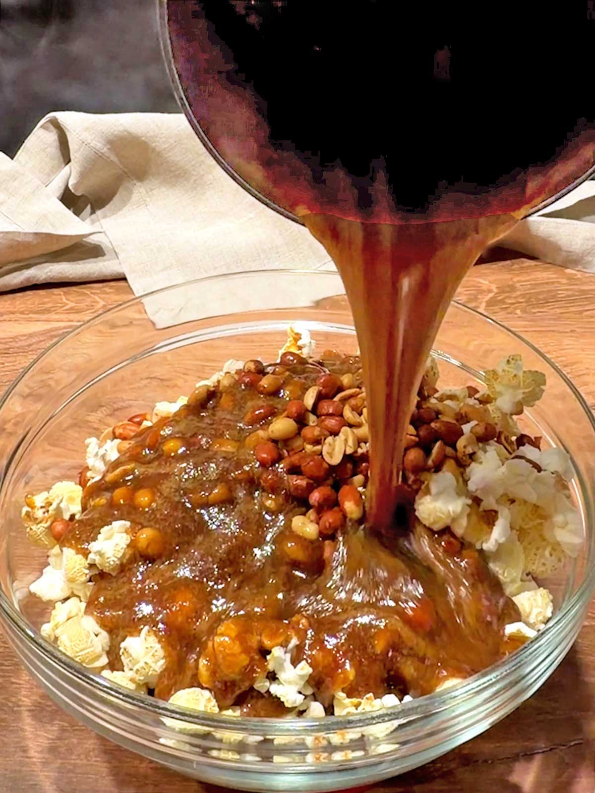 Pouring caramel over popcorn and peanuts.