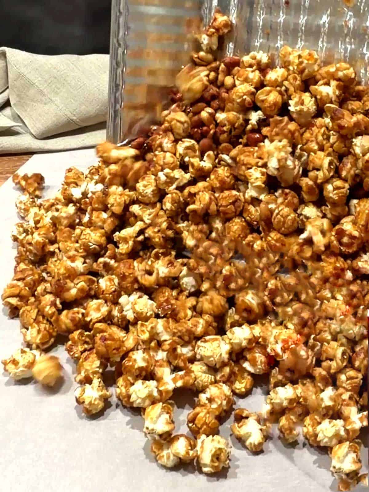Transferring the caramel corn to a piece of parchment paper to cool.