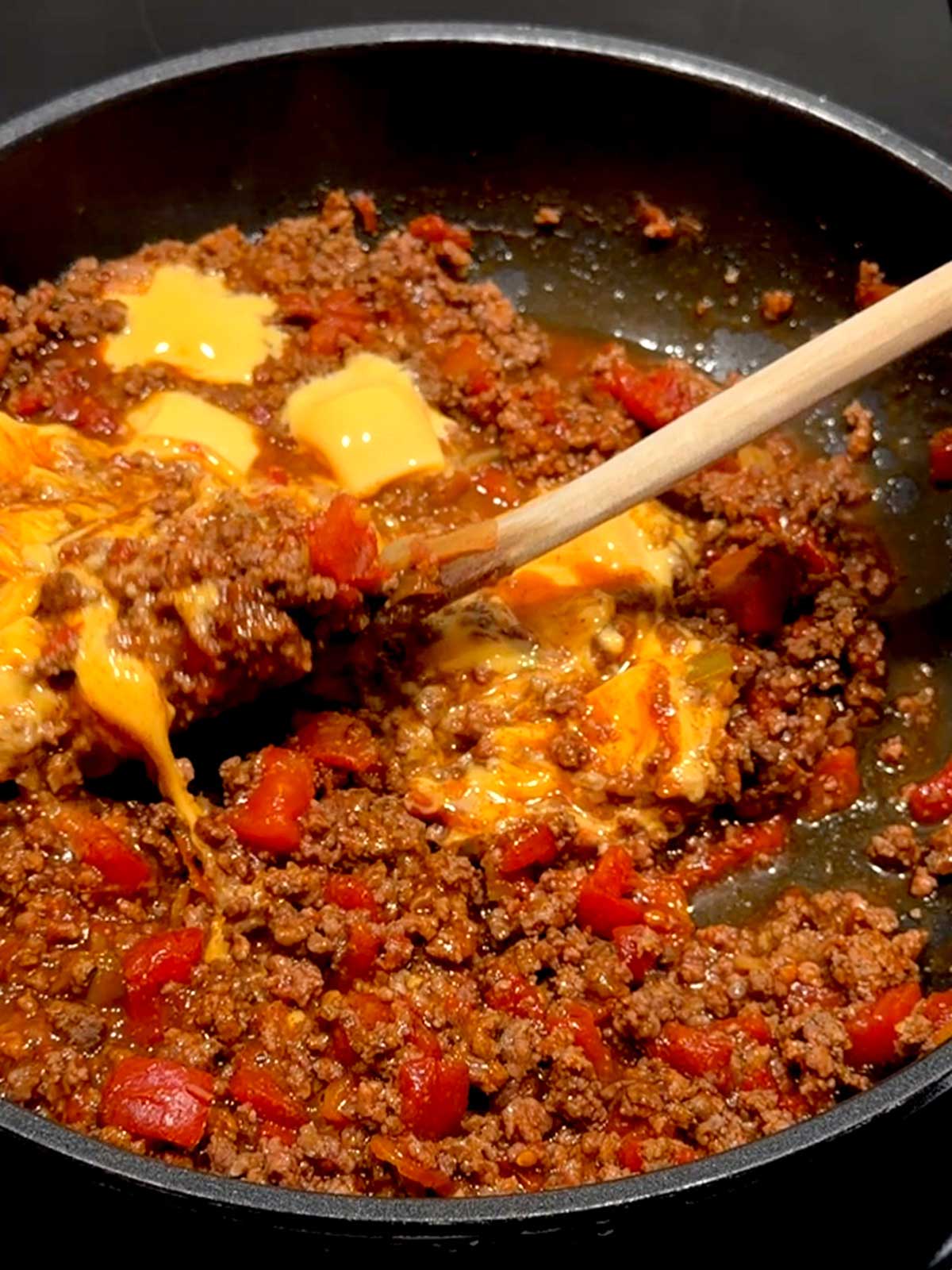 Stirring melted Velveeta into the taco mixture.