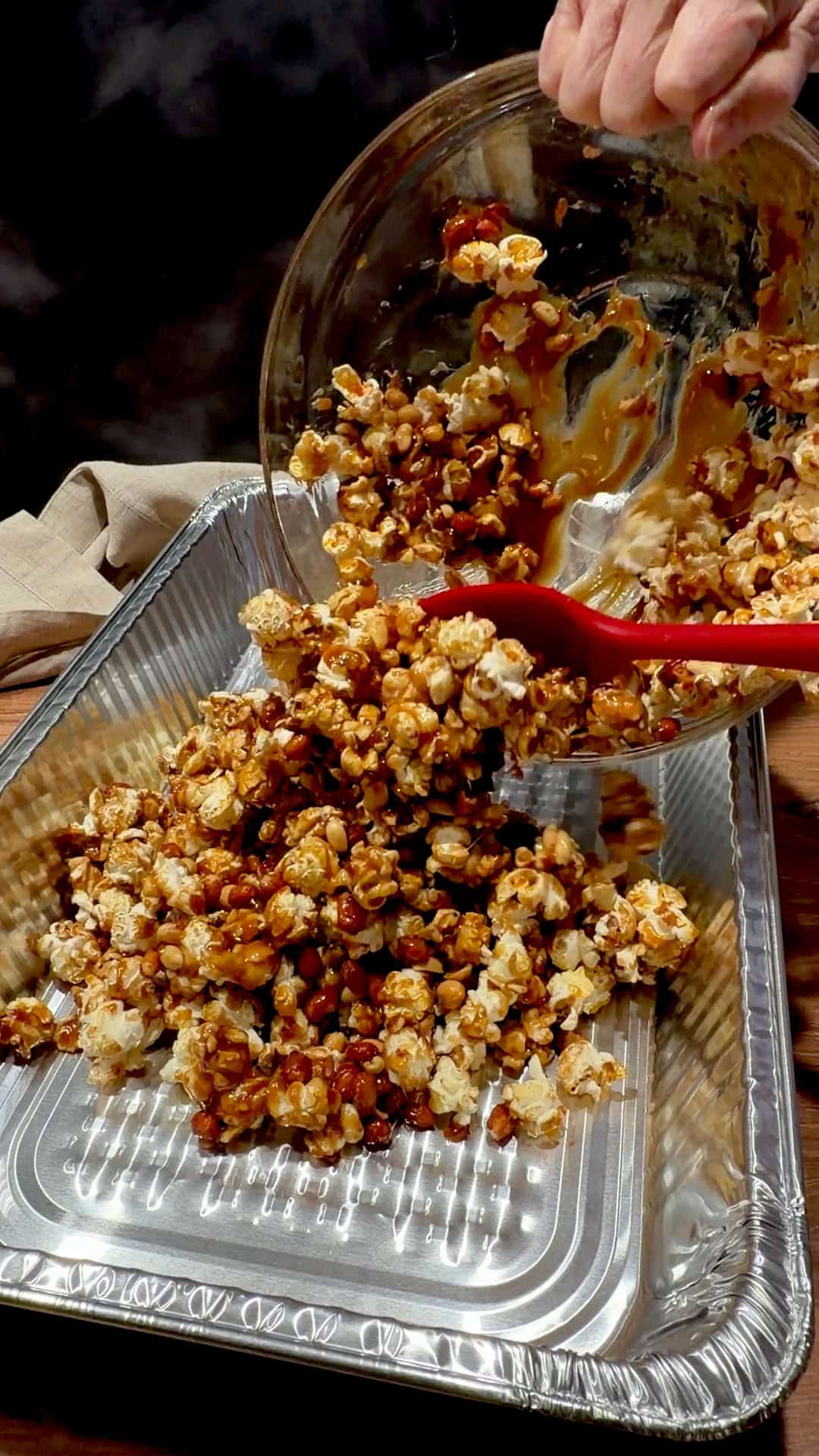 Transferring coated popcorn and peanuts to a disposable aluminum pan.