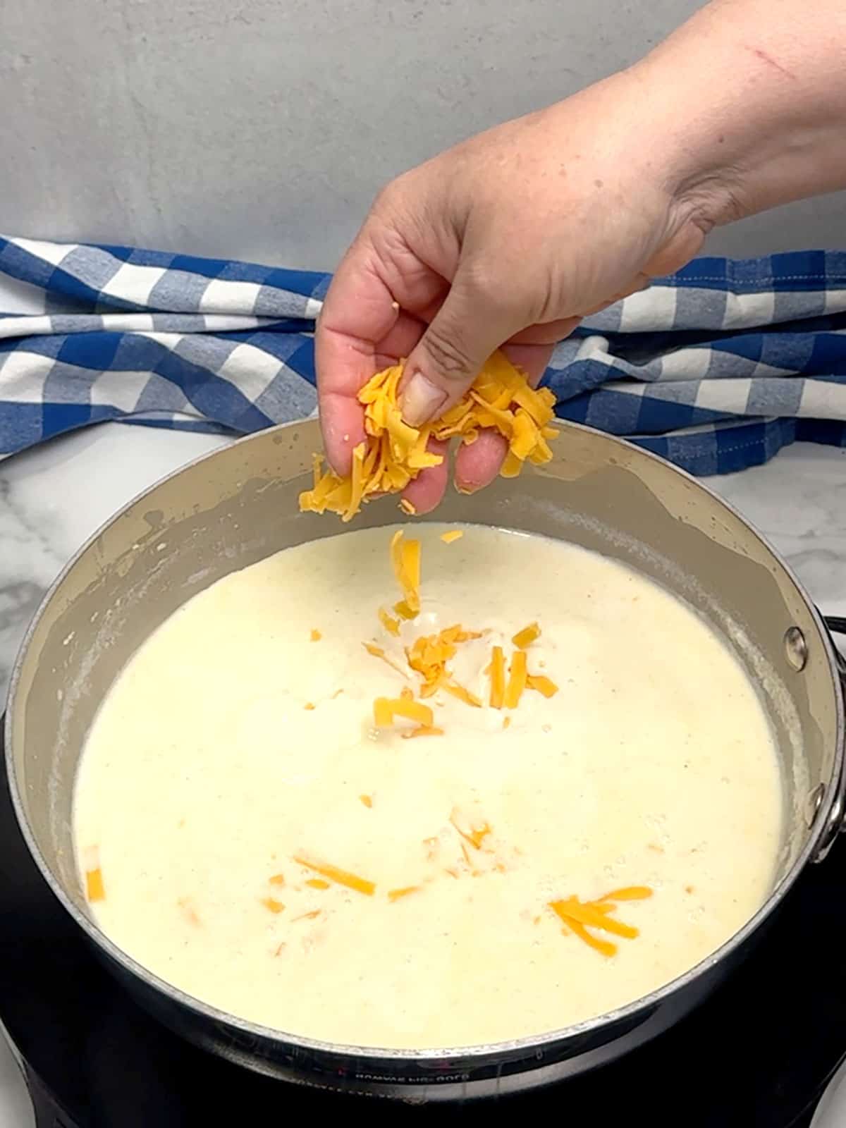 adding cheese to milk mixture to create cheese sauce