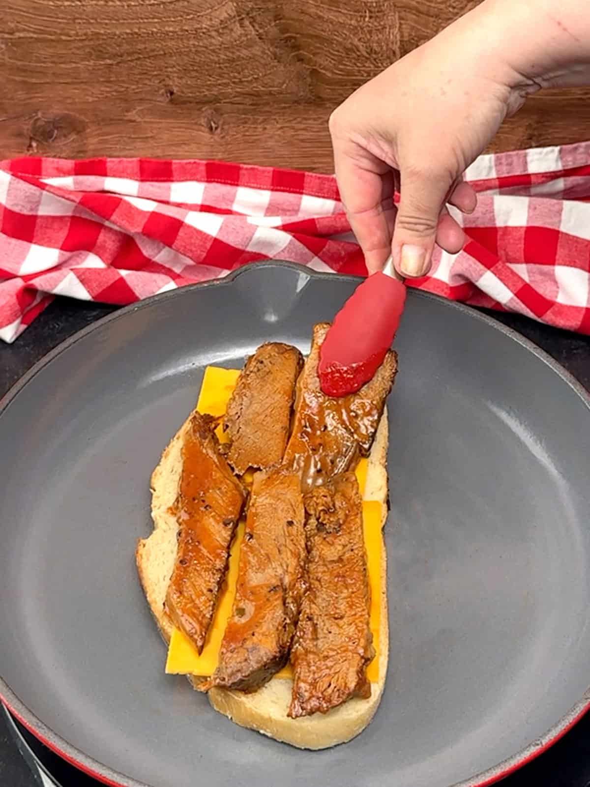 placing heated brisket on top of cheddar cheese