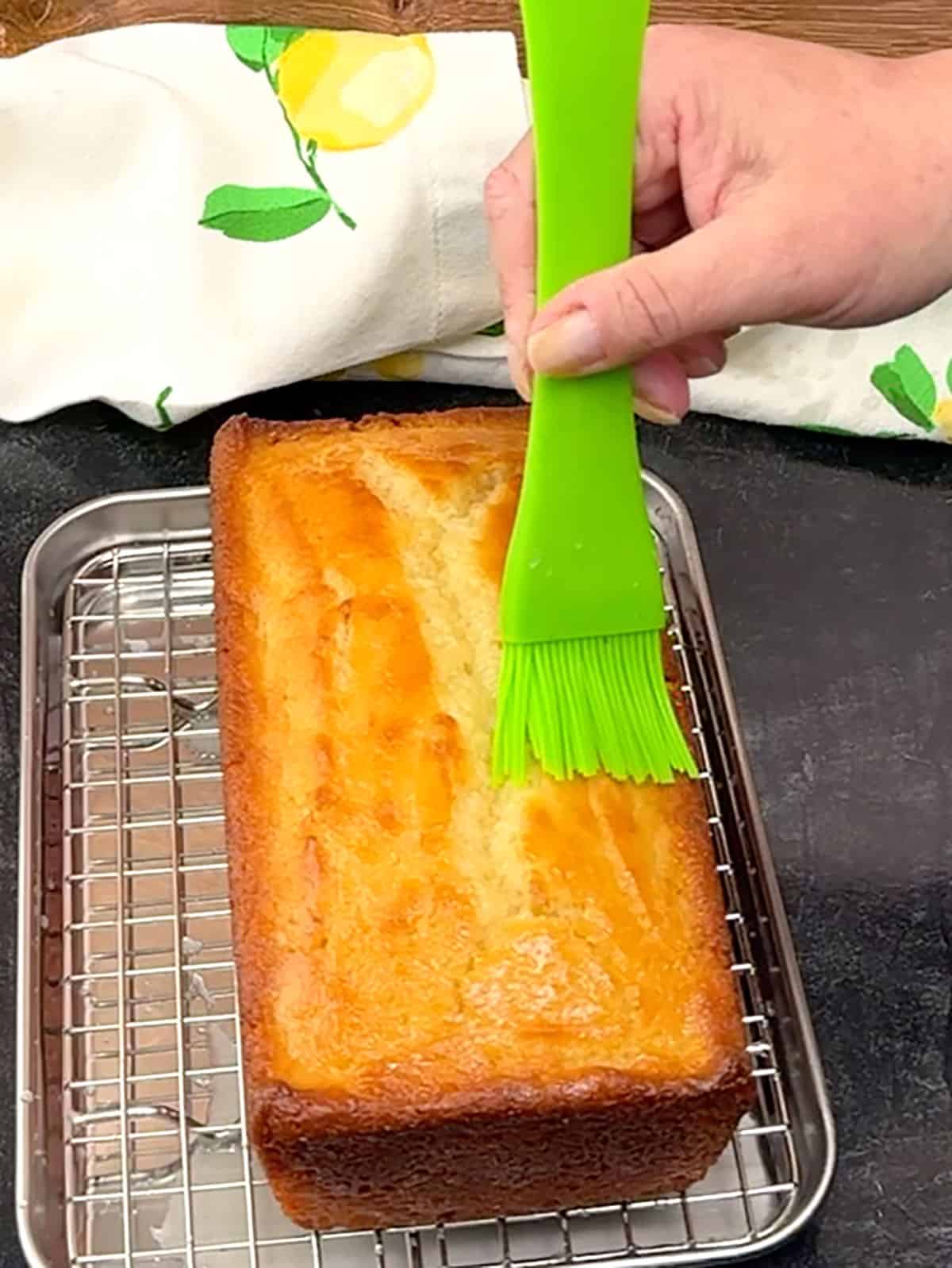 brushing lemon syrup over cake