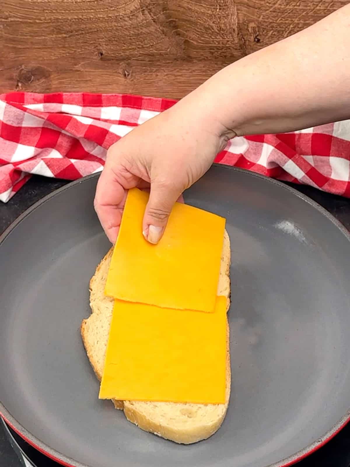 placing cheddar cheese onto prepared bread in skillet