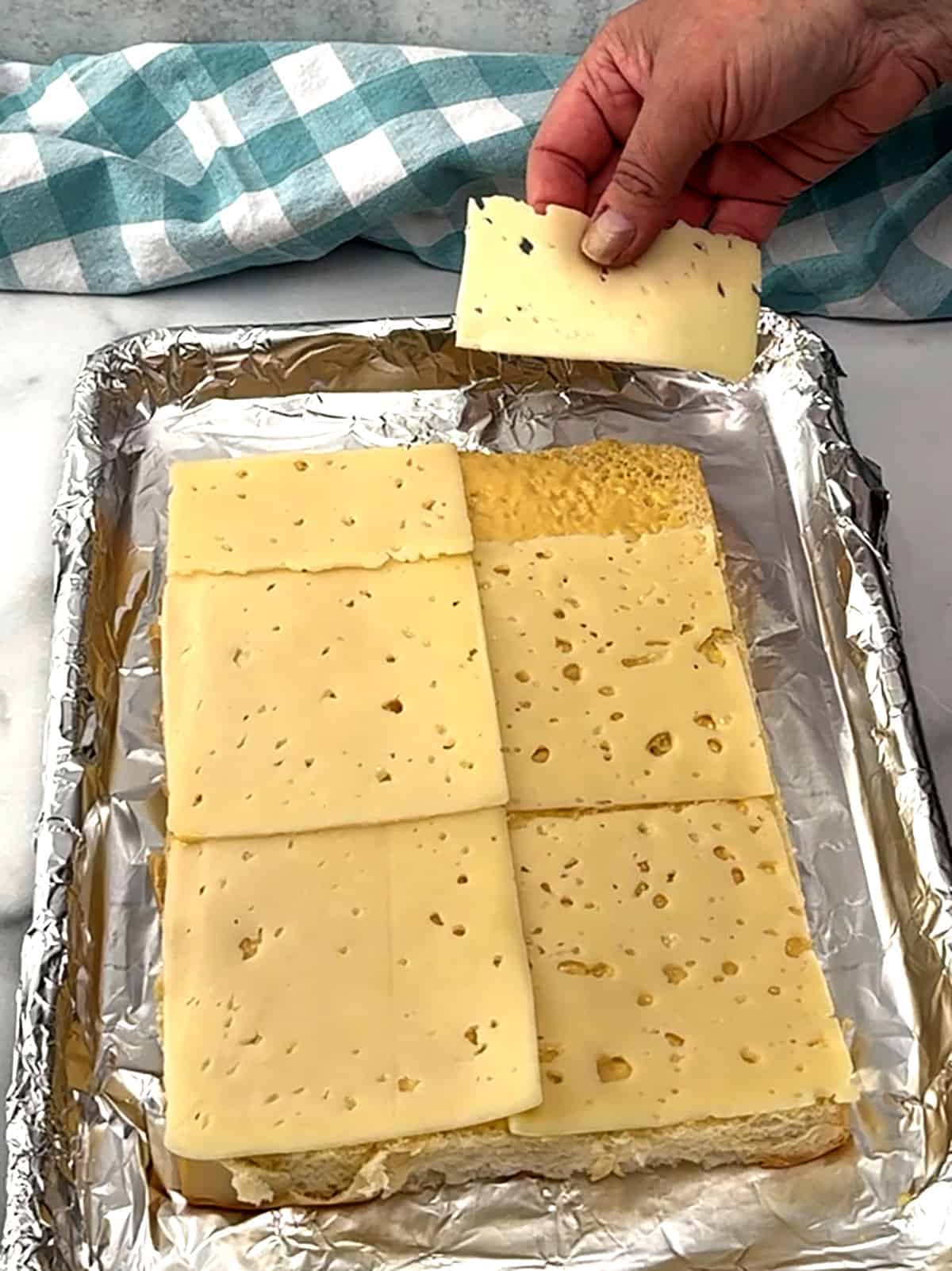 placing cheese on top of sauce on buns