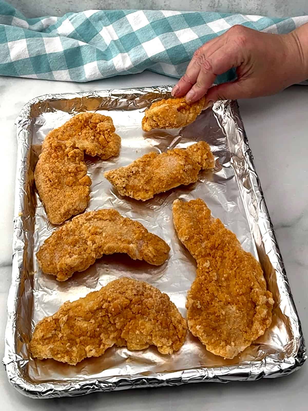 placing frozen chicken tenders on prepared baking sheet