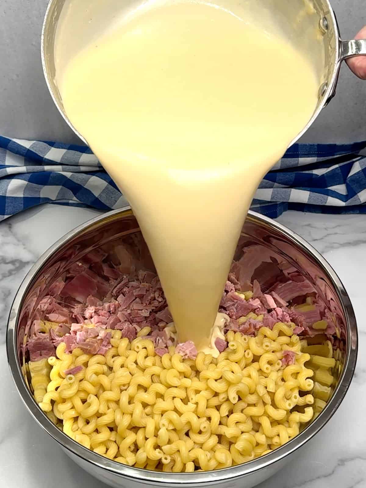 combining pasta, ham, and cheese sauce