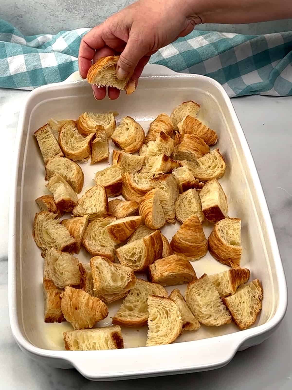 sprinkling half of the croissant pieces into the bottom of the prepared baking dish