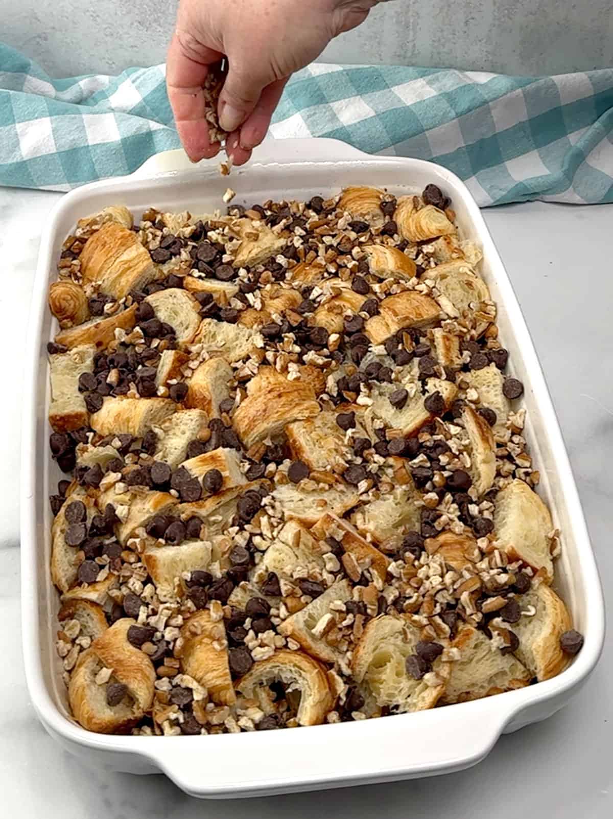 adding remaining croissant pieces, chocolate chips and pecan pieces in pan