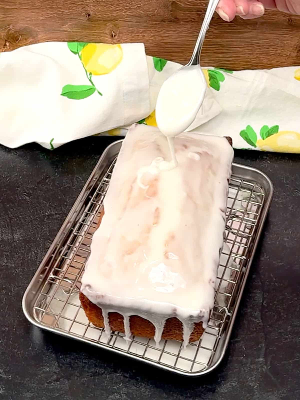 spooning glaze over the top of the better Than Starbucks Lemon Loaf
