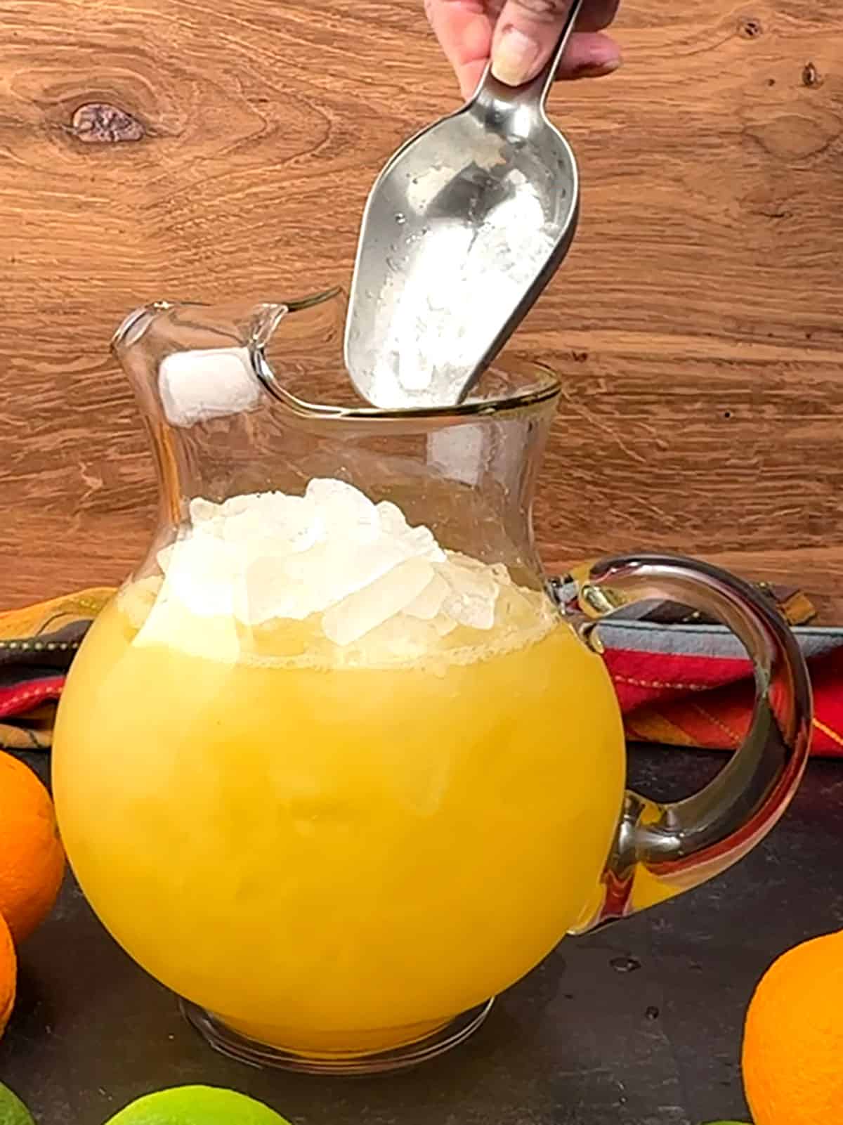 adding ice and margarita mocktail to a pitcher