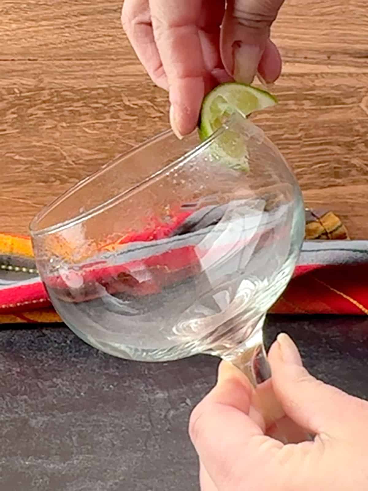 rubbing lime juice around the edge of a glass