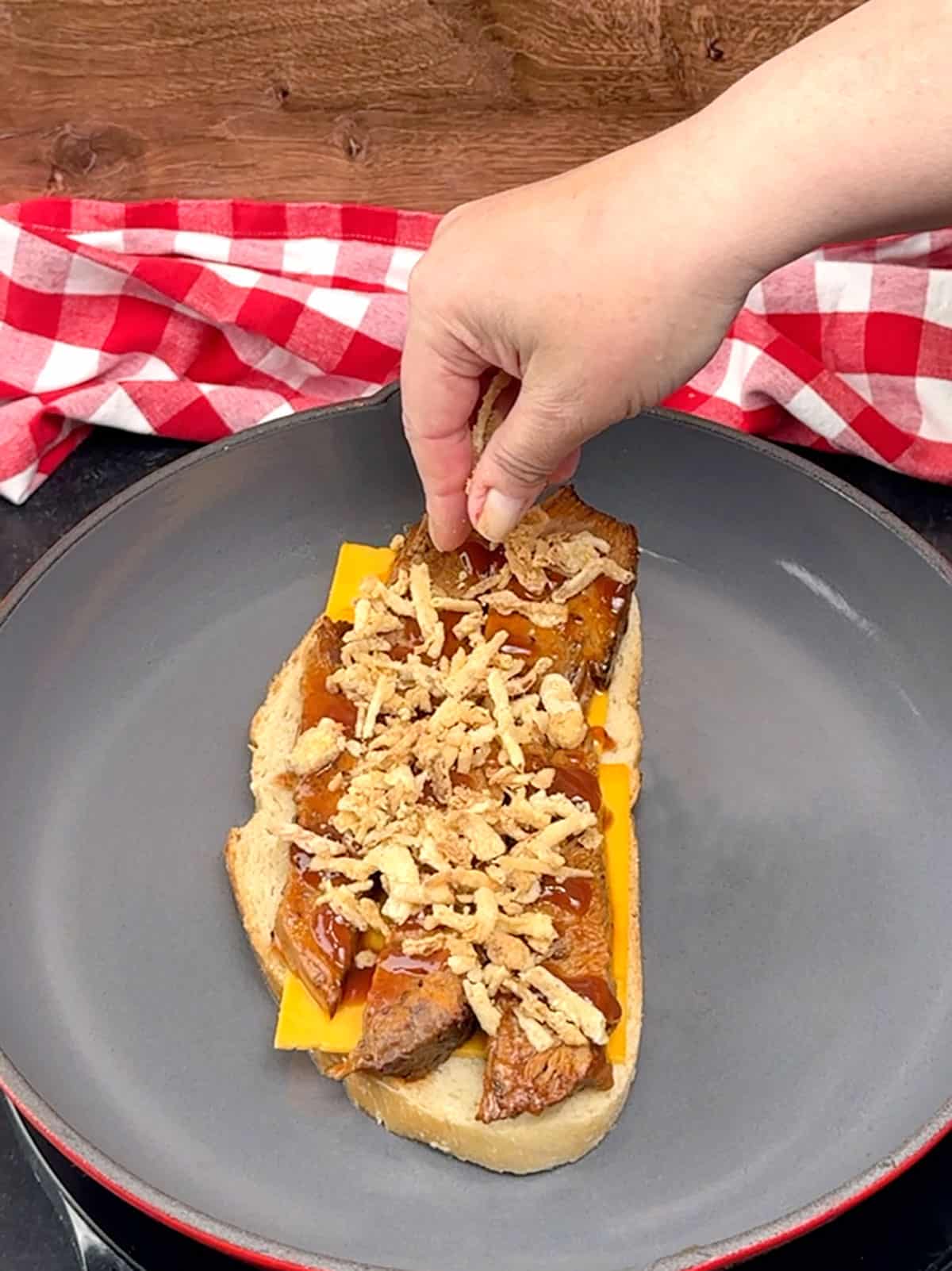 sprinkling french's crispy fried onions over sauce covered brisket