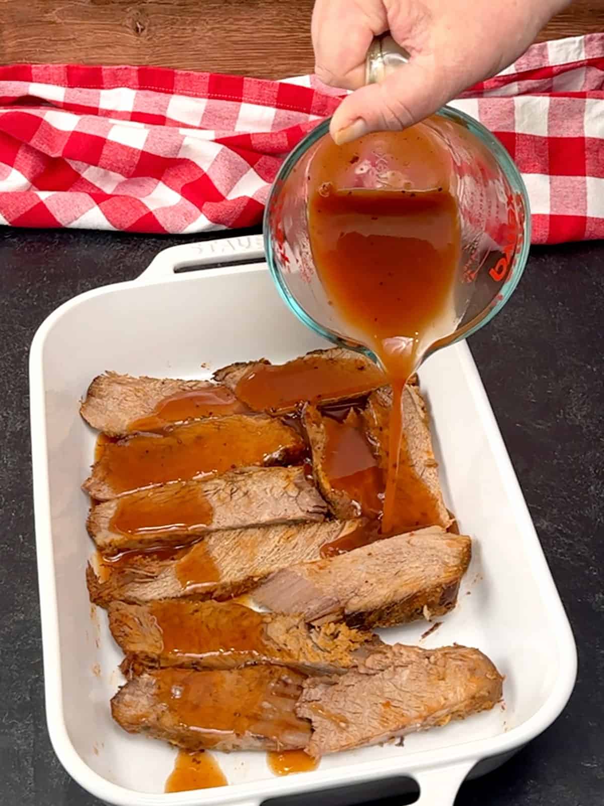 pouring liquid over brisket slices