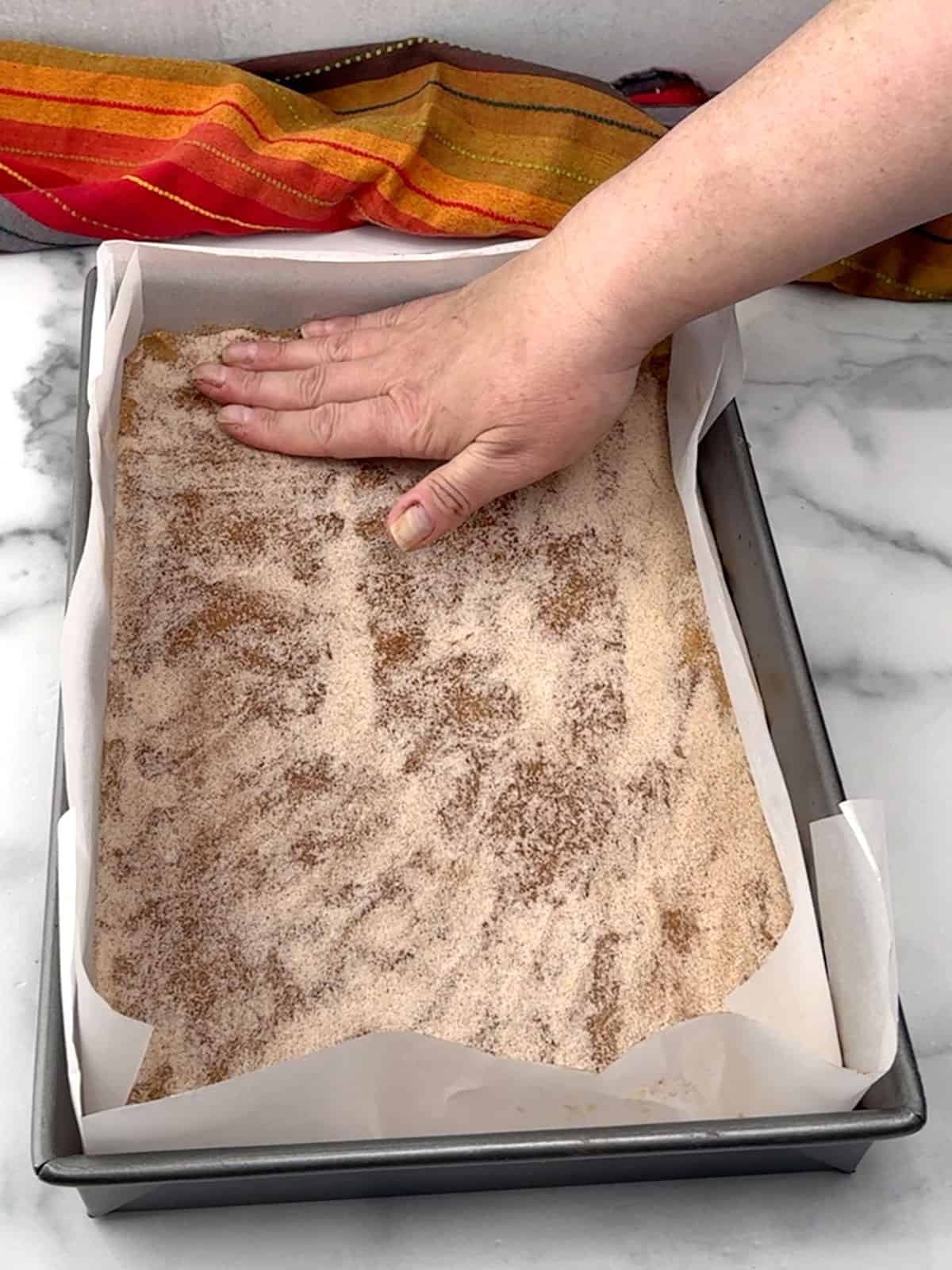 spreading cinnamon-sugar topping over dough