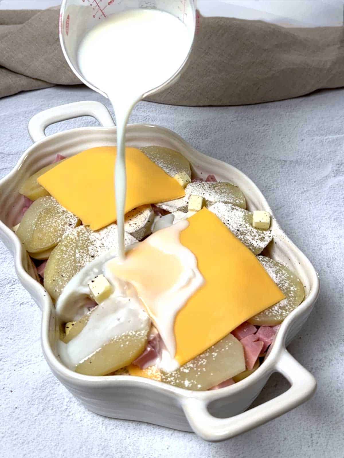 Pouring milk on casserole.