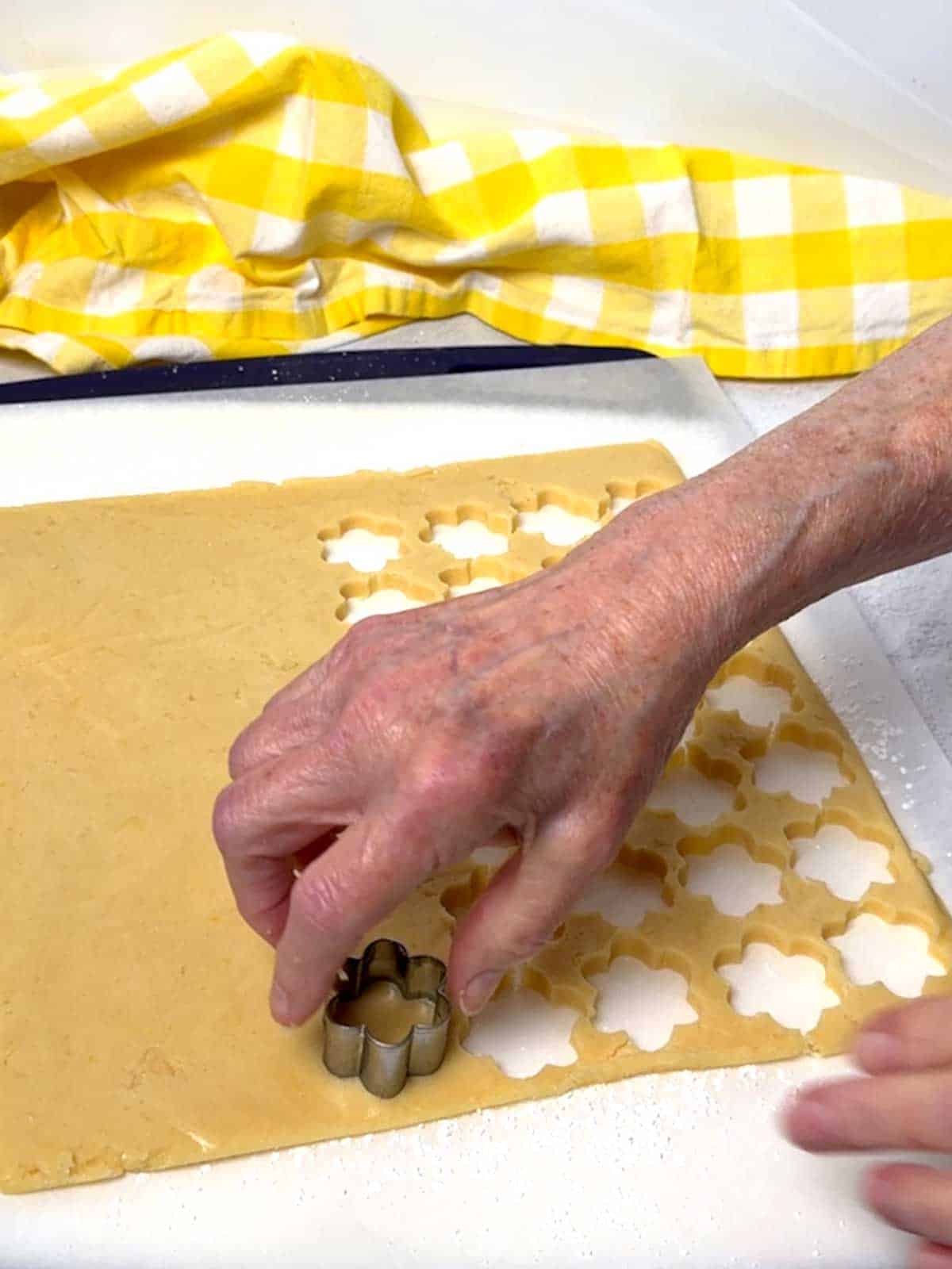 Cutting the dough into shapes with a flower cookie cutter.