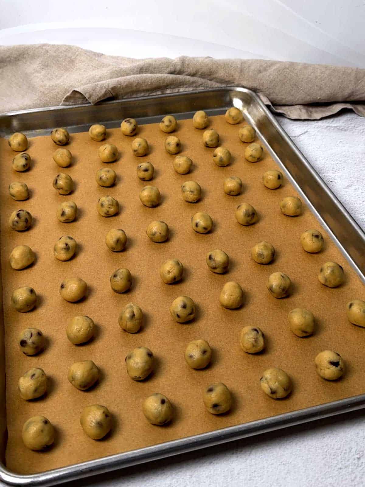 Portioned cookie dough on a parchment-lined half-sheet pan.