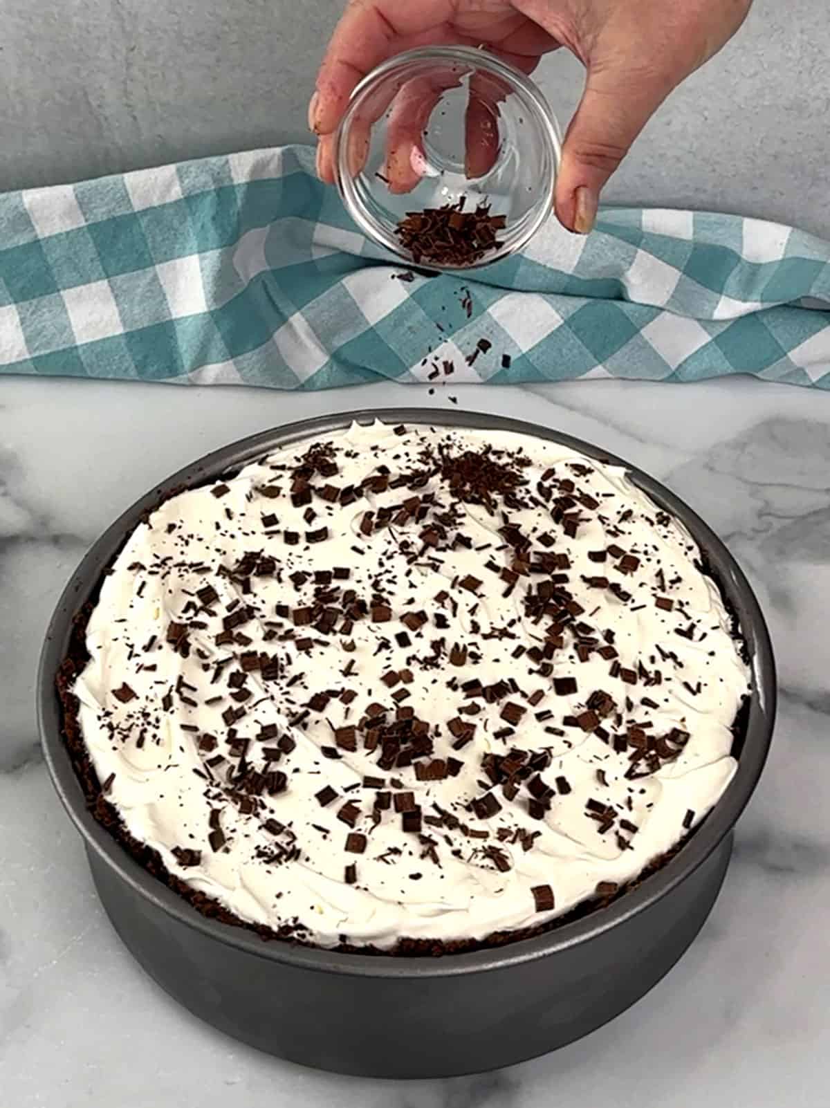 topping Easy No-Bake Chocolate Cheesecake with shaved chocolate curls