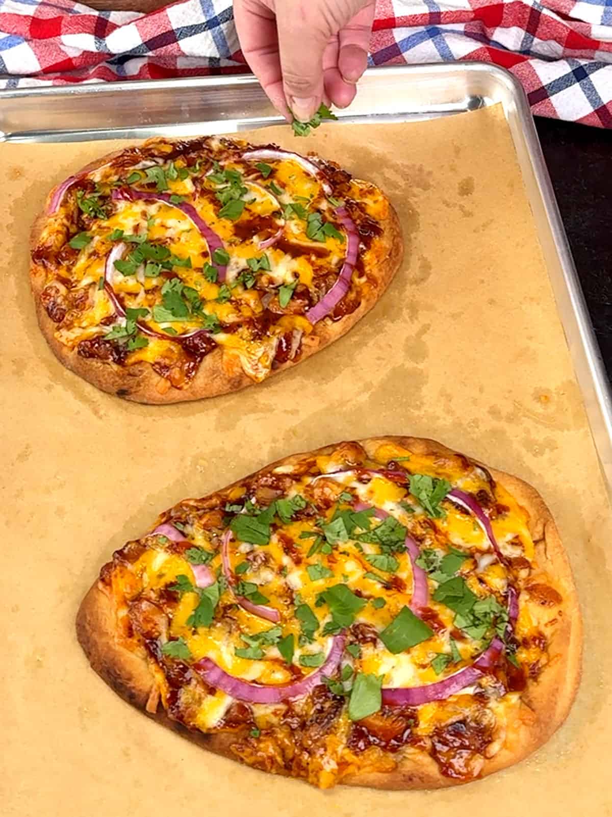 sprinkling cilantro over the cooked pizzas.