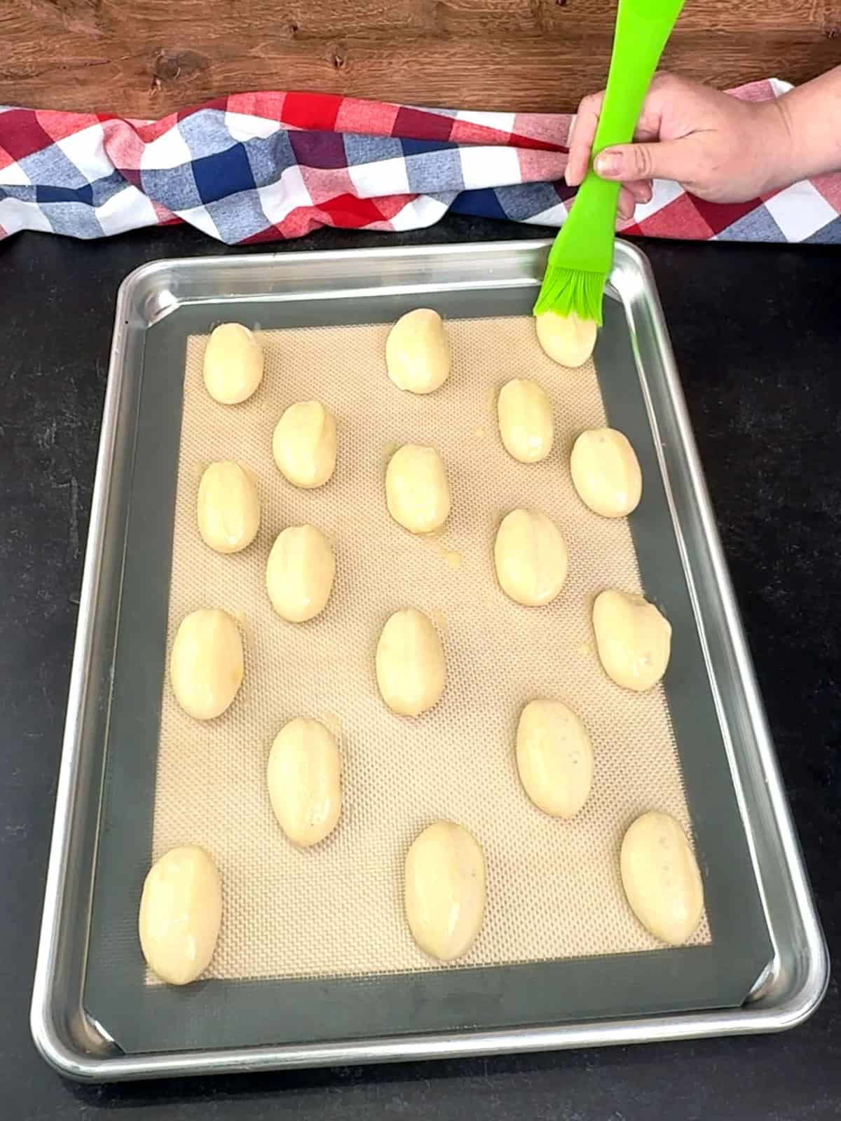 brushing egg wash over the buns