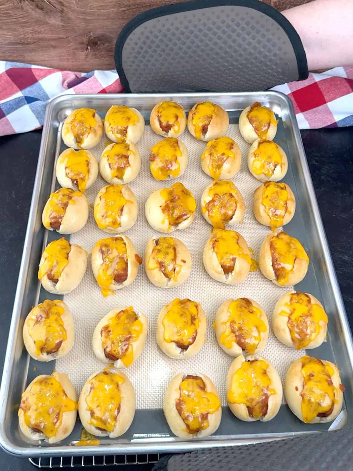 Removing Mini Chili Cheese Dog Sliders from the oven