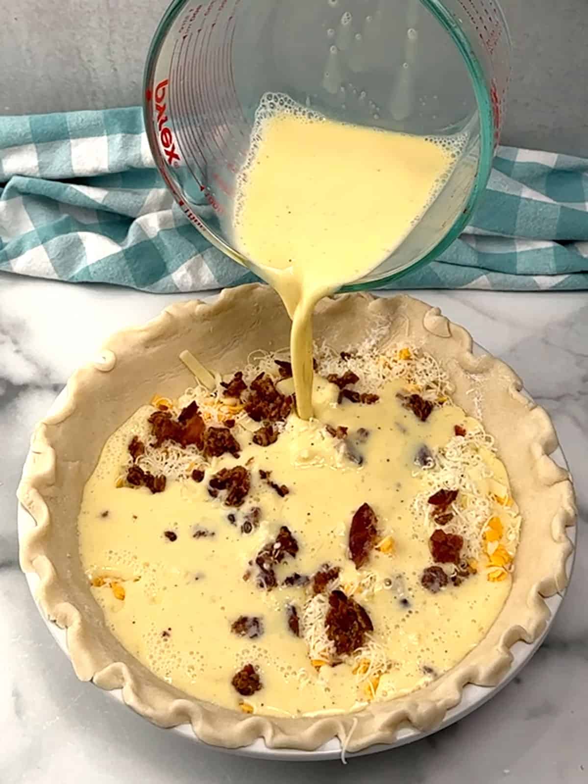 pouring egg mixture into the filled crust