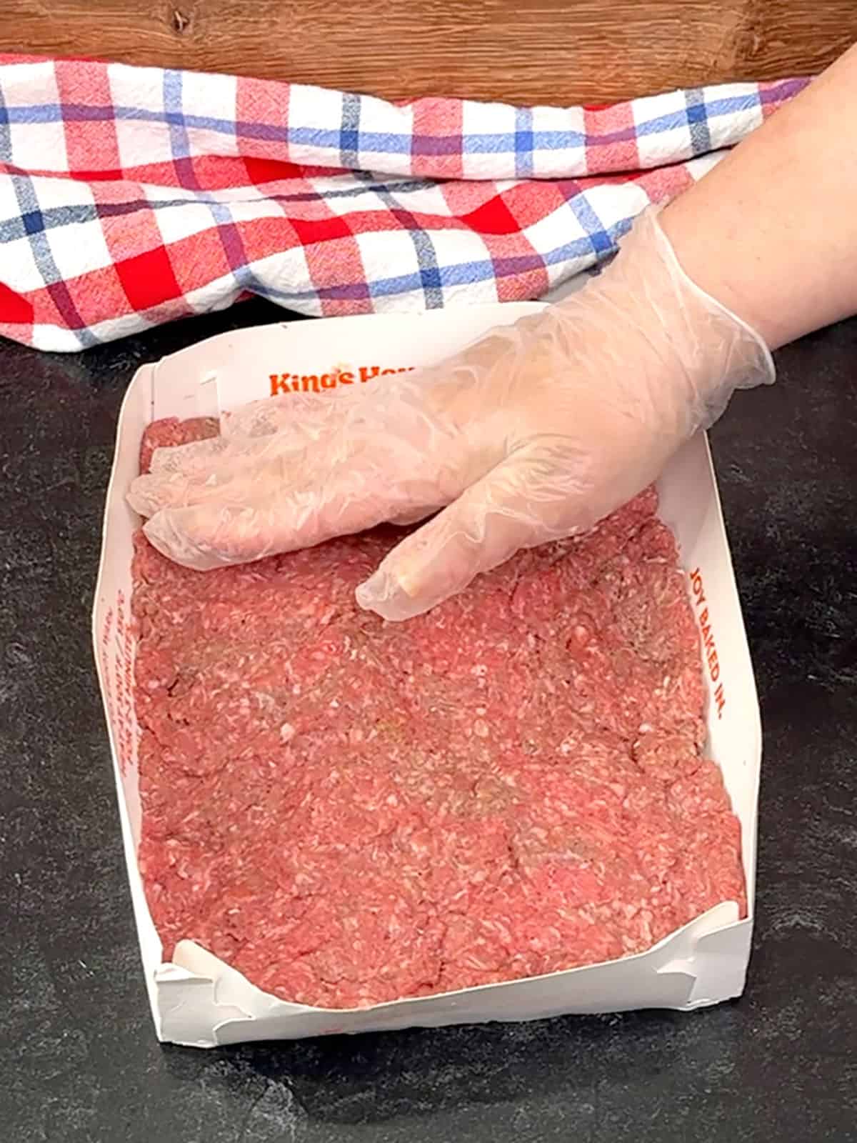 pressing raw meat into slider bun tray