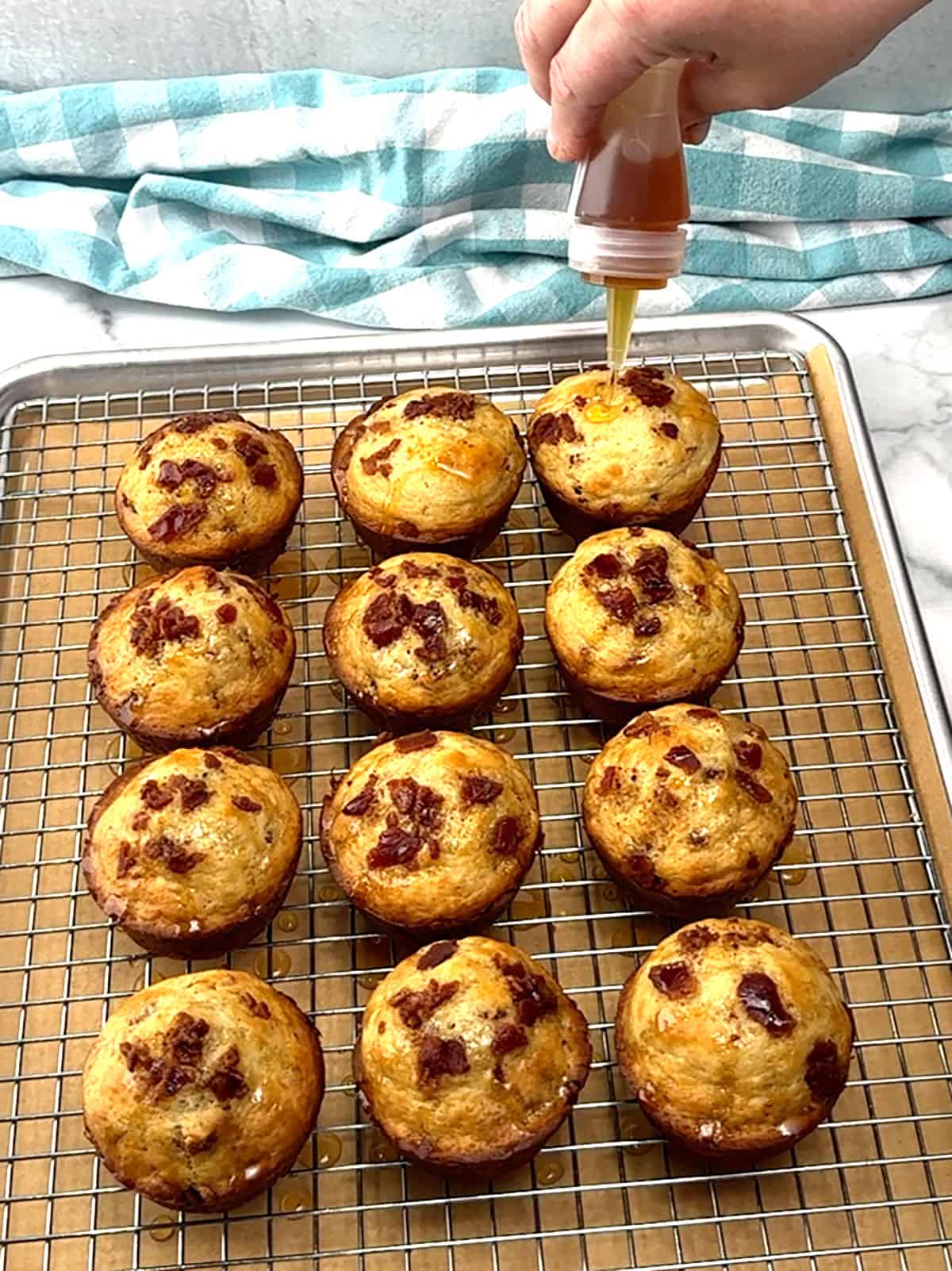 topping warm muffins with maple syrup