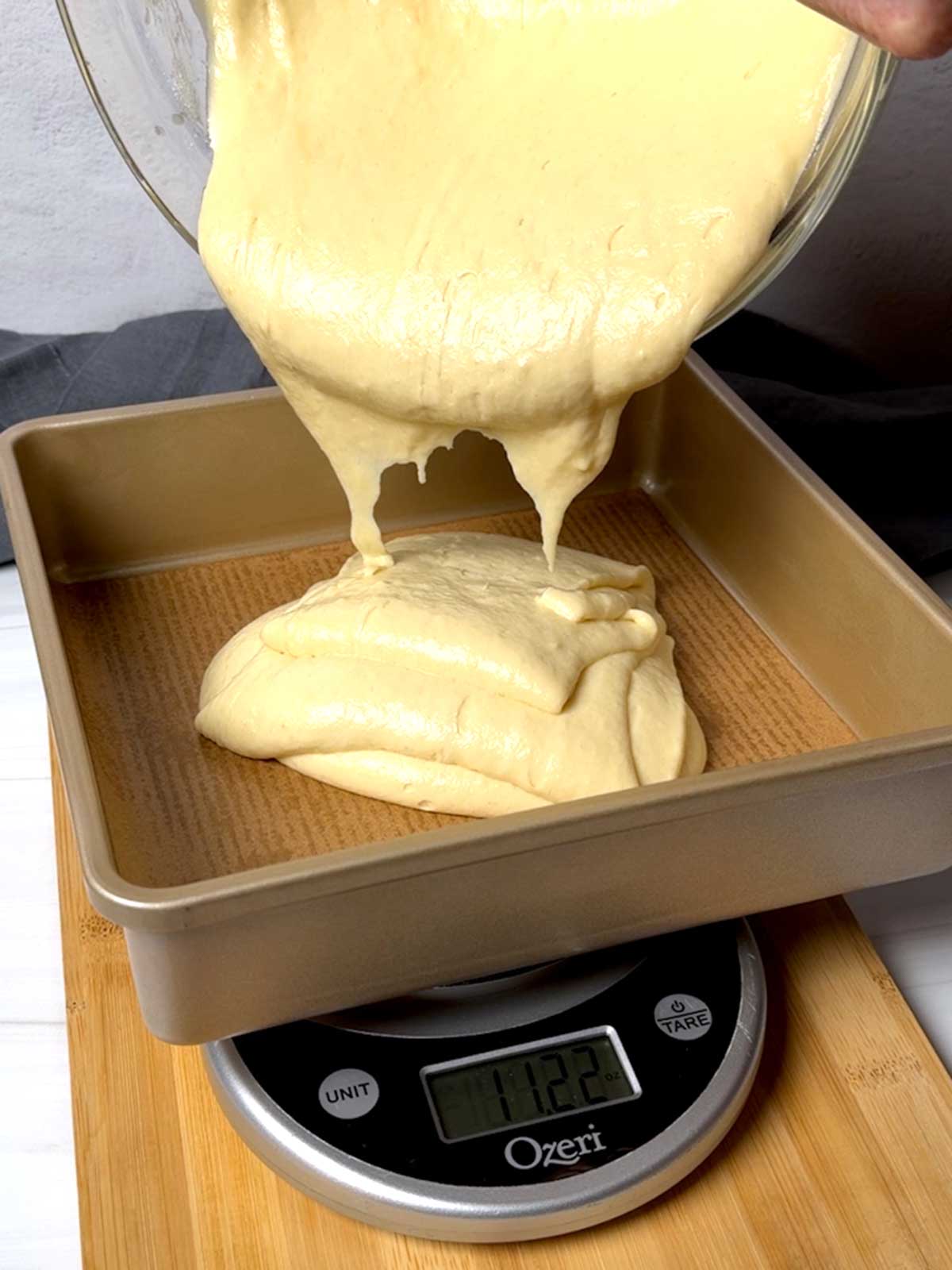 Adding cake batter to the prepared pans.
