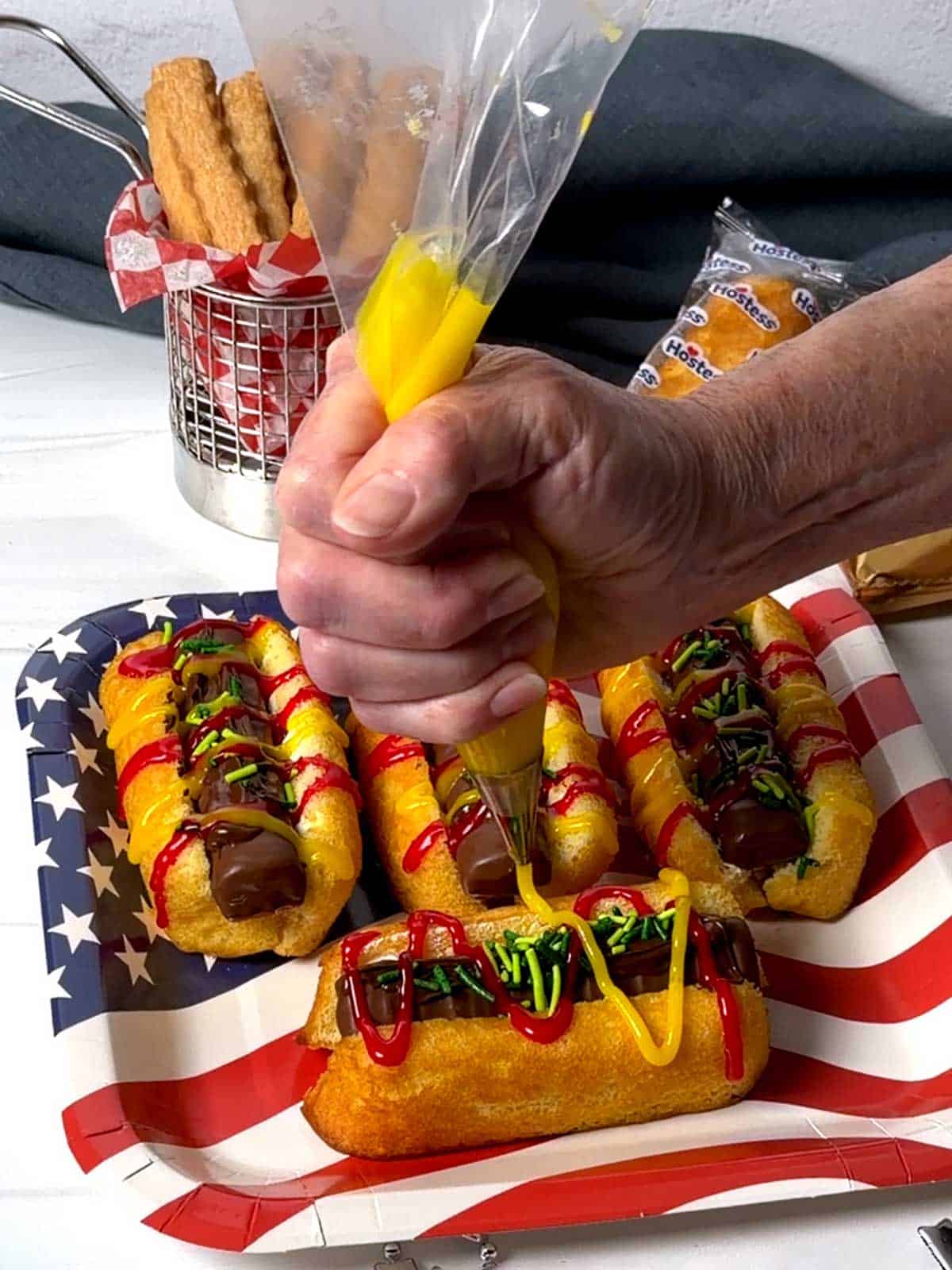 Piping yellow decorating icing on the Twinkie Dog.