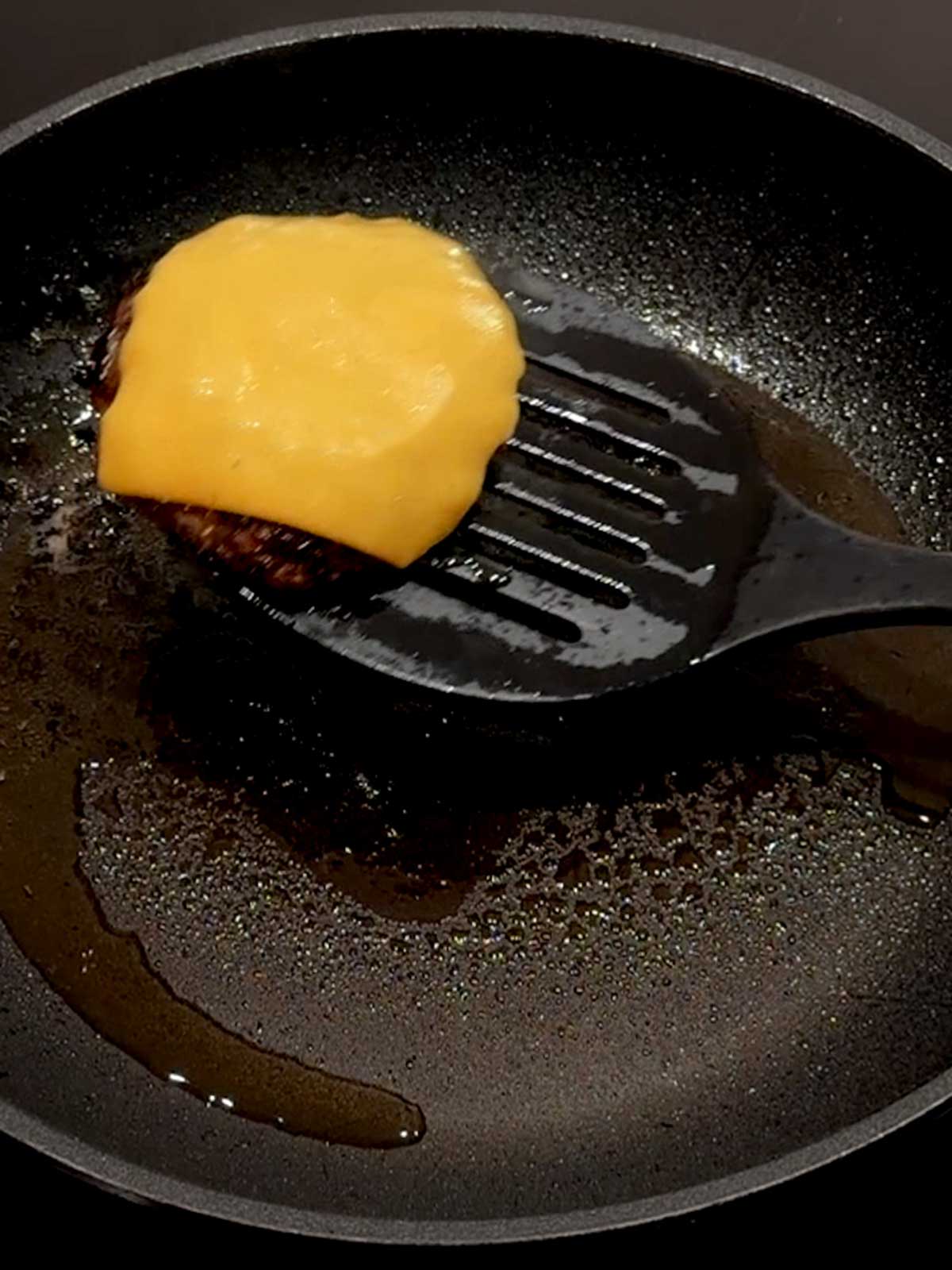 Burger topped iwith cheese out of the pan