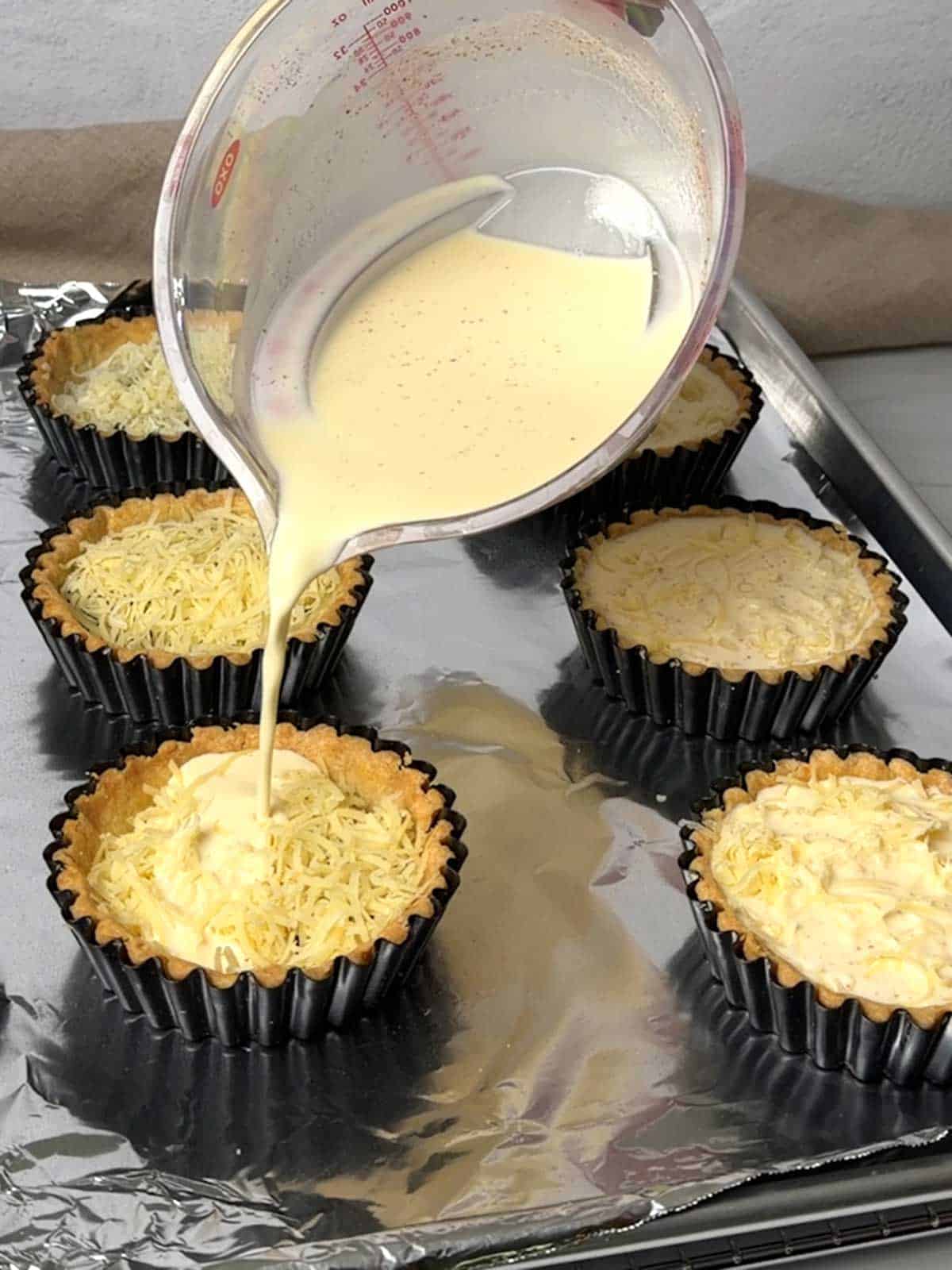Pouring custard in the mini tart shells.