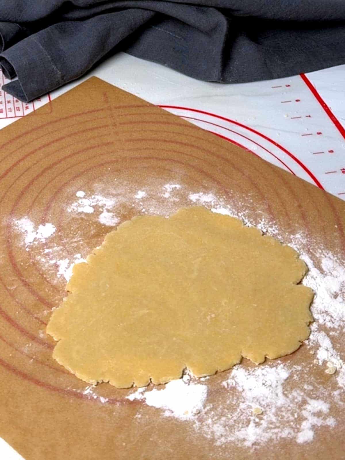 Rolled piece of dough on floured parchment paper.