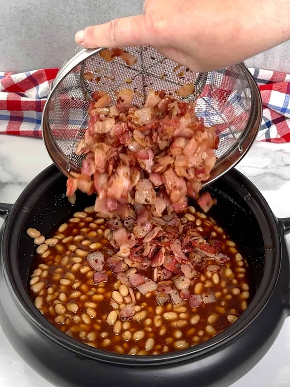 adding beans and bacon mixture to the crockpot