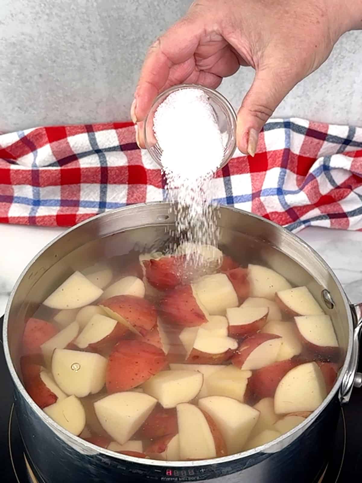 adding Kosher salt to potatoes in water
