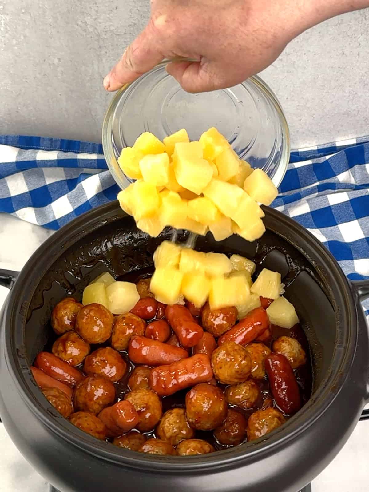 adding drained pineapple to crockpot