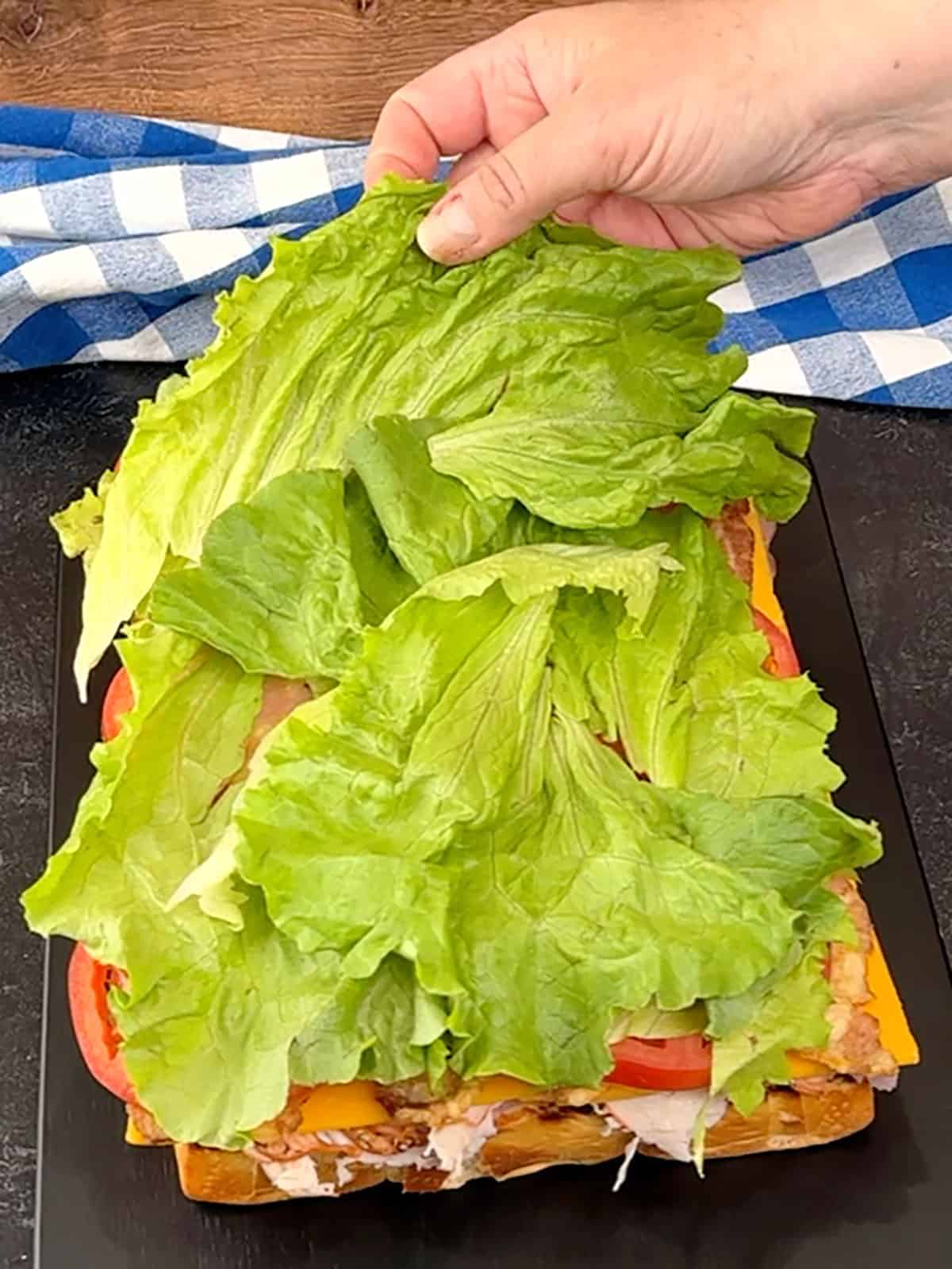 placing lettuce on top of tomatoes
